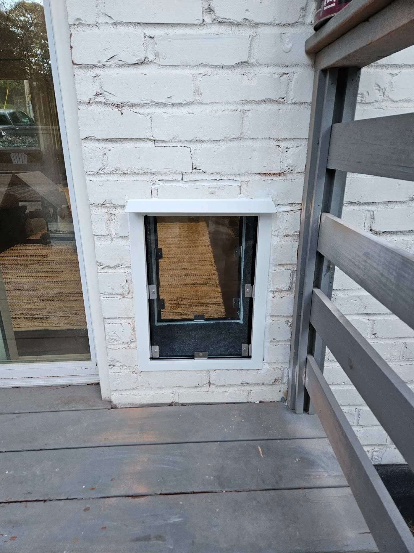 A pet door professionally installed in a white-painted brick wall