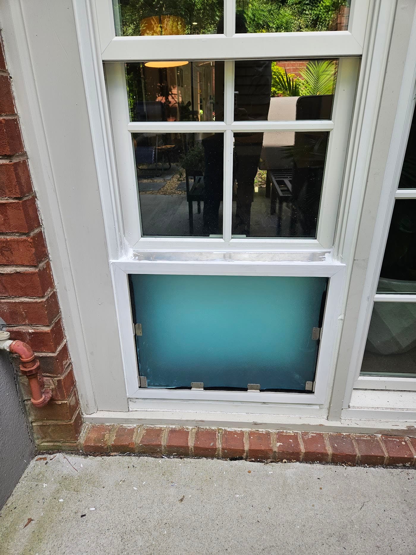 A pet door fitted beneath a window with a brick surround