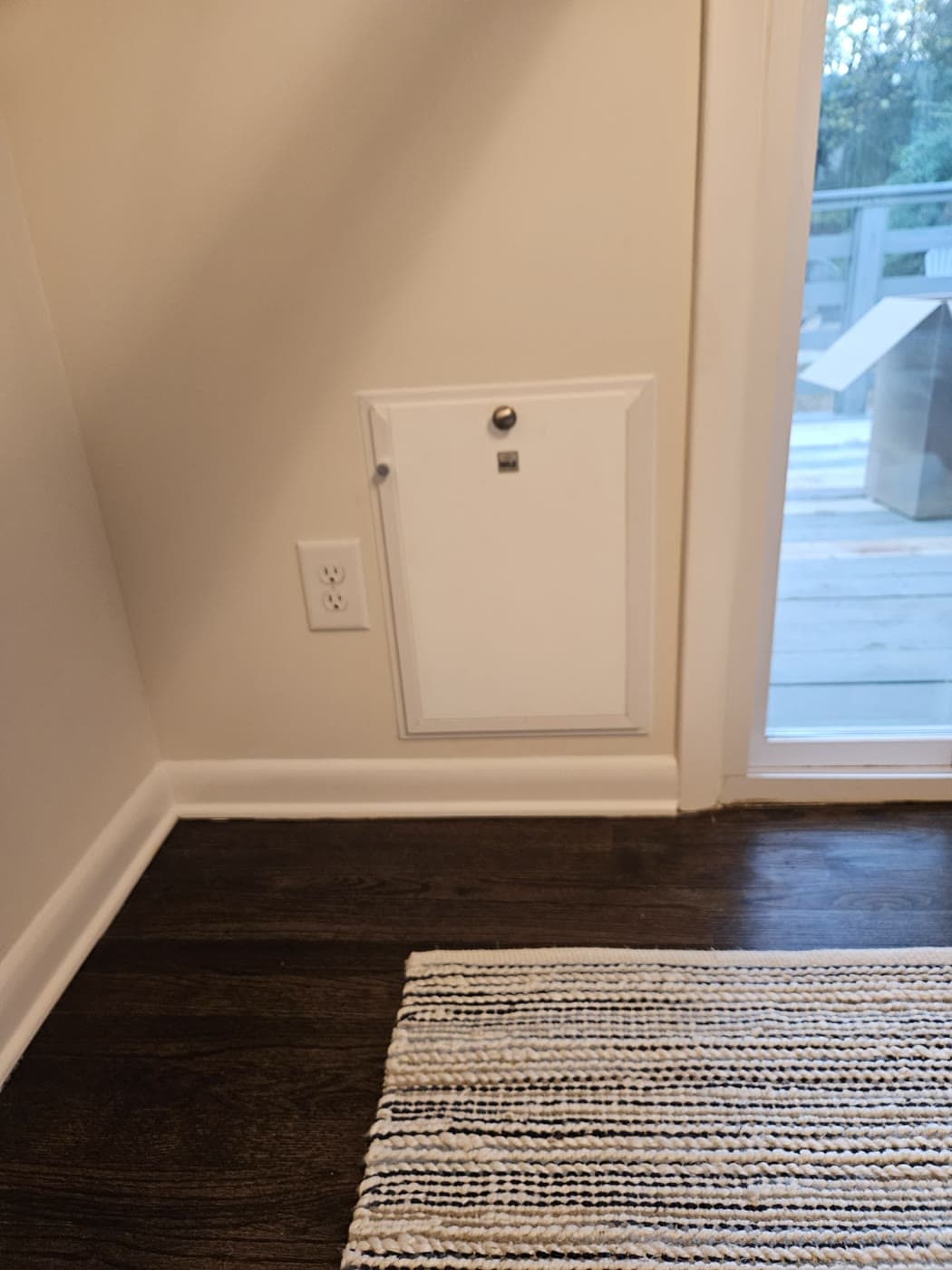 A pet door fitted through a wall beside a glass patio door